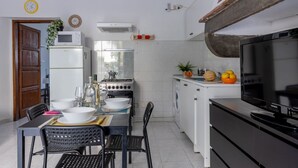 A compact kitchen with a dining area, a microwave, a stove, a washing machine, and a television. - GuestHost - Spacious 50 sqm apartment, ideal for 4 people, located on the ground floor of a building WITHOUT lift (NOT suitable for disabled people). The apartment is located a 9-minute walk from Pisa-Galileo Galilei airport and 6 minutes by public trans (Pisa)