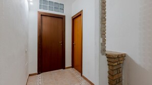 Un pasillo con una puerta de madera, una puerta más pequeña y una chimenea de ladrillo.