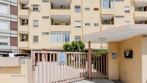 Una entrada cerrada a un edificio residencial de varios pisos, con balcones y unidades de aire acondicionado.