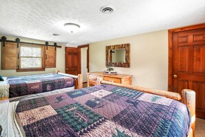 A bedroom with two beds, a dresser, a mirror, and a door.
