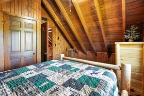 Une pièce en bois avec un lit, une porte en bois et un plafond en pente.