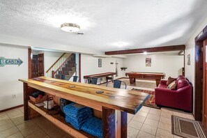 En rummelig opholdsstue med et træbord, en rød sofa og en trappe til et andet værelse.