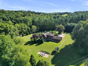 A large, two-story log cabin with a well-maintained lawn and a fire pit area.