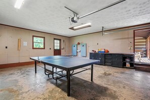 En rummelig stue med et ping pong-bord, vægpaneler og en trædør.