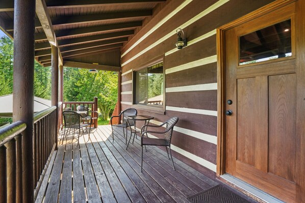 A wooden deck with outdoor furniture, a door, and a window.