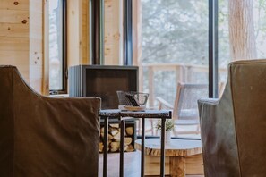 A cozy cabin interior with a fireplace, leather chairs, and a wooden table with a basket.
