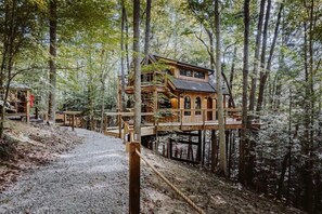 Una estructura de casa en árbol de madera elevada sobre pilares en un entorno boscoso.