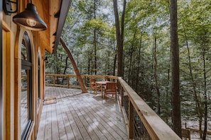 A wooden deck with a table and chairs, surrounded by trees. - The Hickory Treehouse w/ Suspension Bridge (South Bloomingville)