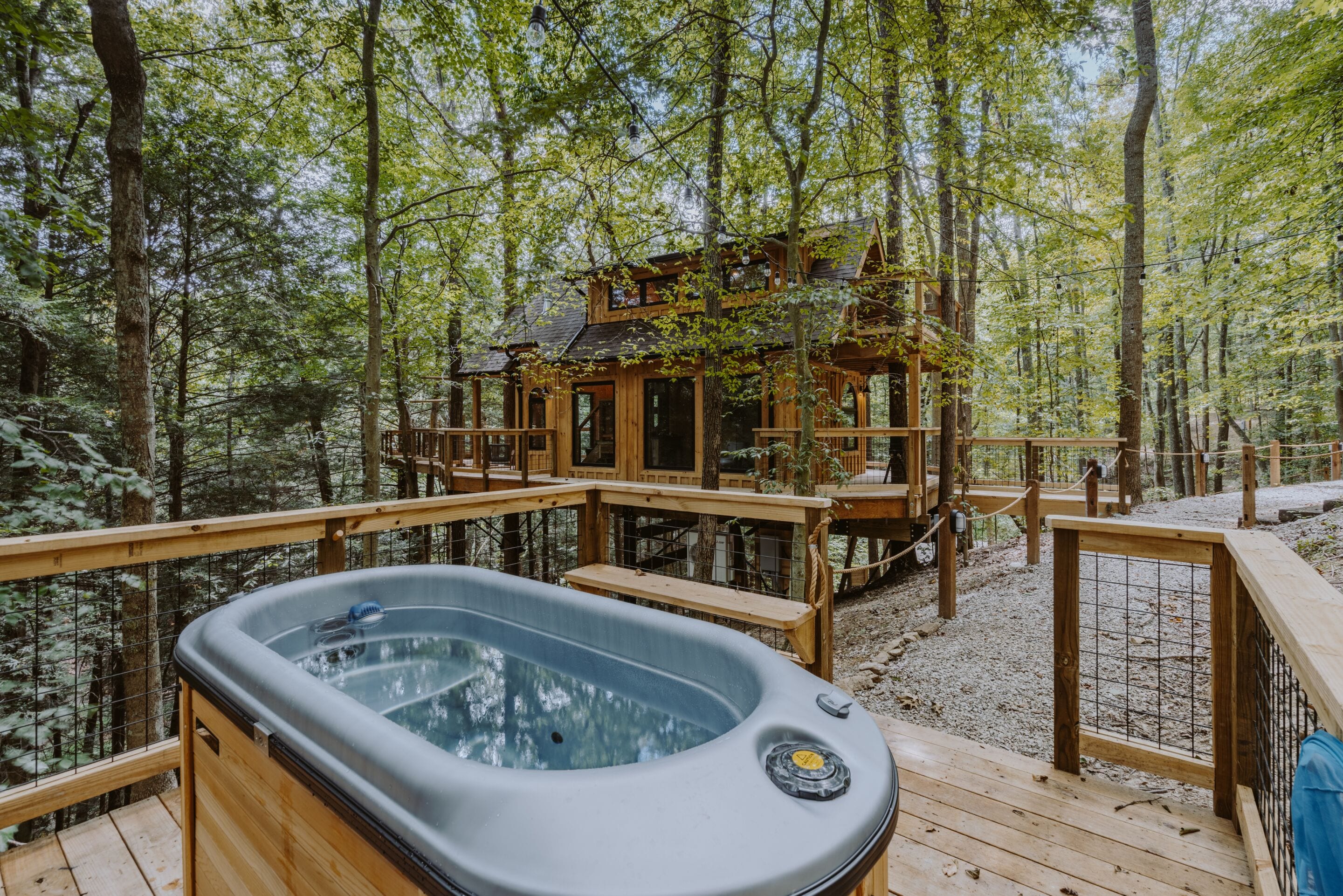 Un jacuzzi en una terraza de madera rodeado de un bosque.