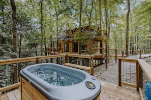 A hot tub on a wooden deck surrounded by a forest. - The Hickory Treehouse w/ Suspension Bridge (South Bloomingville)