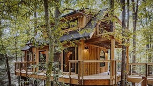 Una casa en el árbol de madera con varios niveles, construida en zona boscosa.