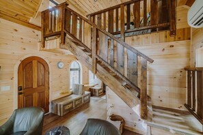 A wooden interior with a staircase, wooden walls, and a bench. - The Hickory Treehouse w/ Suspension Bridge (South Bloomingville)