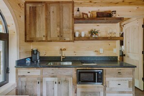 A wooden kitchen with a built-in microwave, a sink, and a coffee maker. - The Hickory Treehouse w/ Suspension Bridge (South Bloomingville)