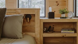 Una habitación de madera acogedora con una cama, una estantería llena de libros, un reloj y una planta pequeña.