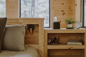 Una habitación de madera acogedora con una cama, una estantería llena de libros, un reloj y una planta pequeña.