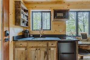 A kitchen with wooden cabinets, a black refrigerator, a microwave, and a coffee maker.