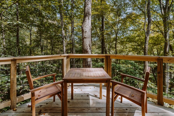A wooden deck with a table and benches overlooking a forest.