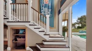 Un escalier avec des rampes blanches et des marches sombres menant à un palier où est suspendu un rideau bleu orné d’un personnage de dessin animé.