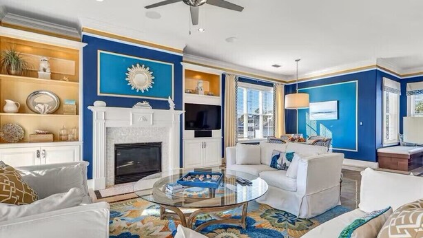 Ein Wohnzimmer mit Kamin, weißen Sofas, einem Glastisch und einer blauen Akzentwand.