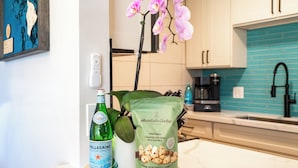 A kitchen counter with a bottle of PELLEGRINO beer, a bag of Honolulu Cookie Company mini bites, and a thank you card. - Hip Hawaiian Oceanfront Vistas (Kihei)