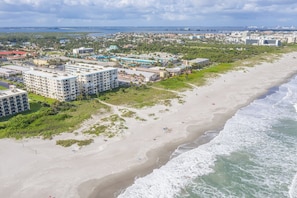 Un hotel frente al mar con varias construcciones, una playa y vistas al océano.