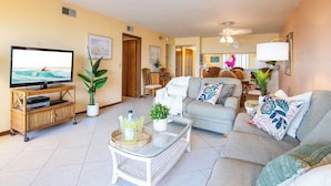 A living room with a TV, sofa, coffee table, and a dining area with chairs and a table.