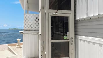 A coastal building with a sliding glass door, a covered porch, and a view of the sea.