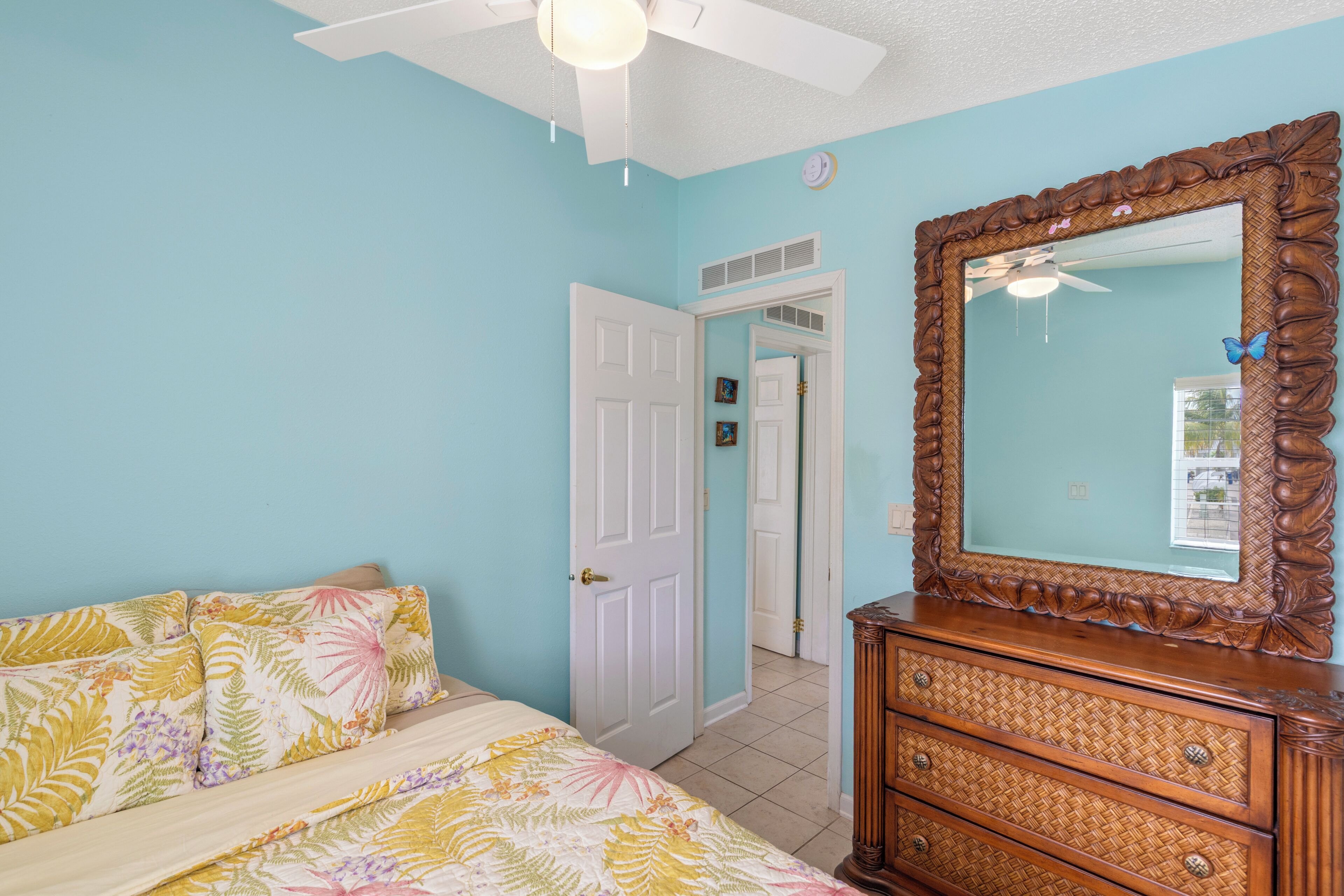 A bedroom with a bed, dresser, and a large mirror.