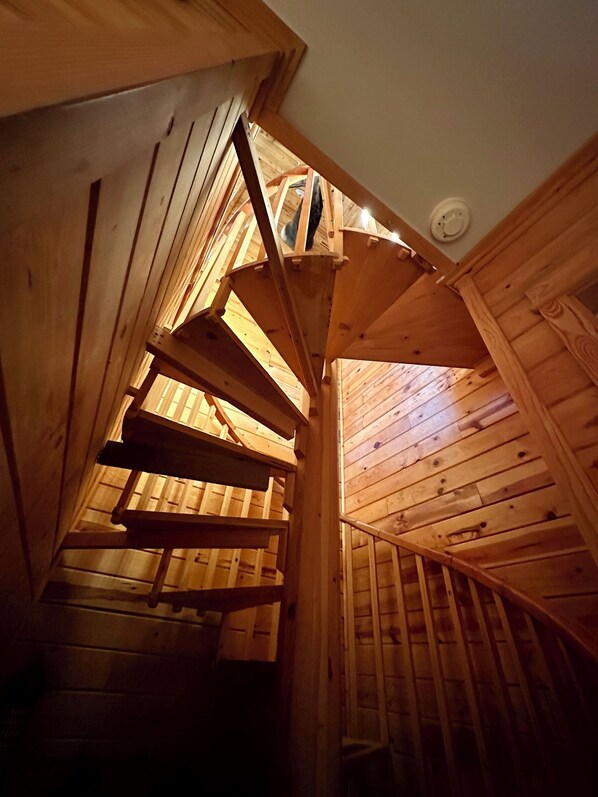Un escalier en bois menant à un plafond incliné percé d’une lucarne.