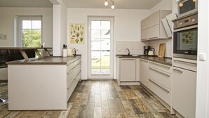 A modern kitchen with white cabinetry, a central island, and a large window.