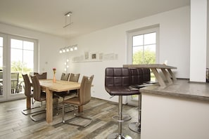 A modern dining area with a wooden table and leather chairs, a bar stool, and a pendant light. - Haus in Idyllischer Lage mit Terrasse und Garten - Villa Vogelblick Haus 01 - Villa Vogelblick (Trent)