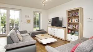 Una sala de estar moderna con un sofá, una mesa de centro, un televisor y una estantería.