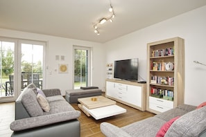 A modern living room with a sofa, a coffee table, a TV, and a bookshelf.