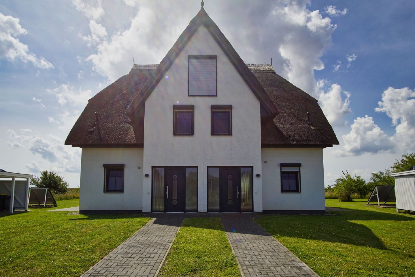 Ein zweistöckiges Haus mit einem steilen Satteldach, einem zentralen Eingang mit Doppeltüren und einem kleinen Fenster im Obergeschoss.
