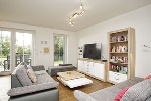 A modern living room with a sofa, a coffee table, a TV, and a bookshelf.