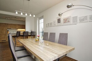 A modern dining area with a wooden table, grey upholstered chairs, and a vase with flowers. - Haus in Idyllischer Lage mit Terrasse und Garten - Villa Vogelblick Haus 02 - Villa Vogelblick (Trent)