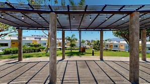 Un espace extérieur abrité, doté d’un sol grillagé, de palmiers et de bâtiments en arrière-plan.