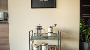 Una zona de cocina con estación de café, que incluye un carrito metálico con equipo para preparar café y recipientes.