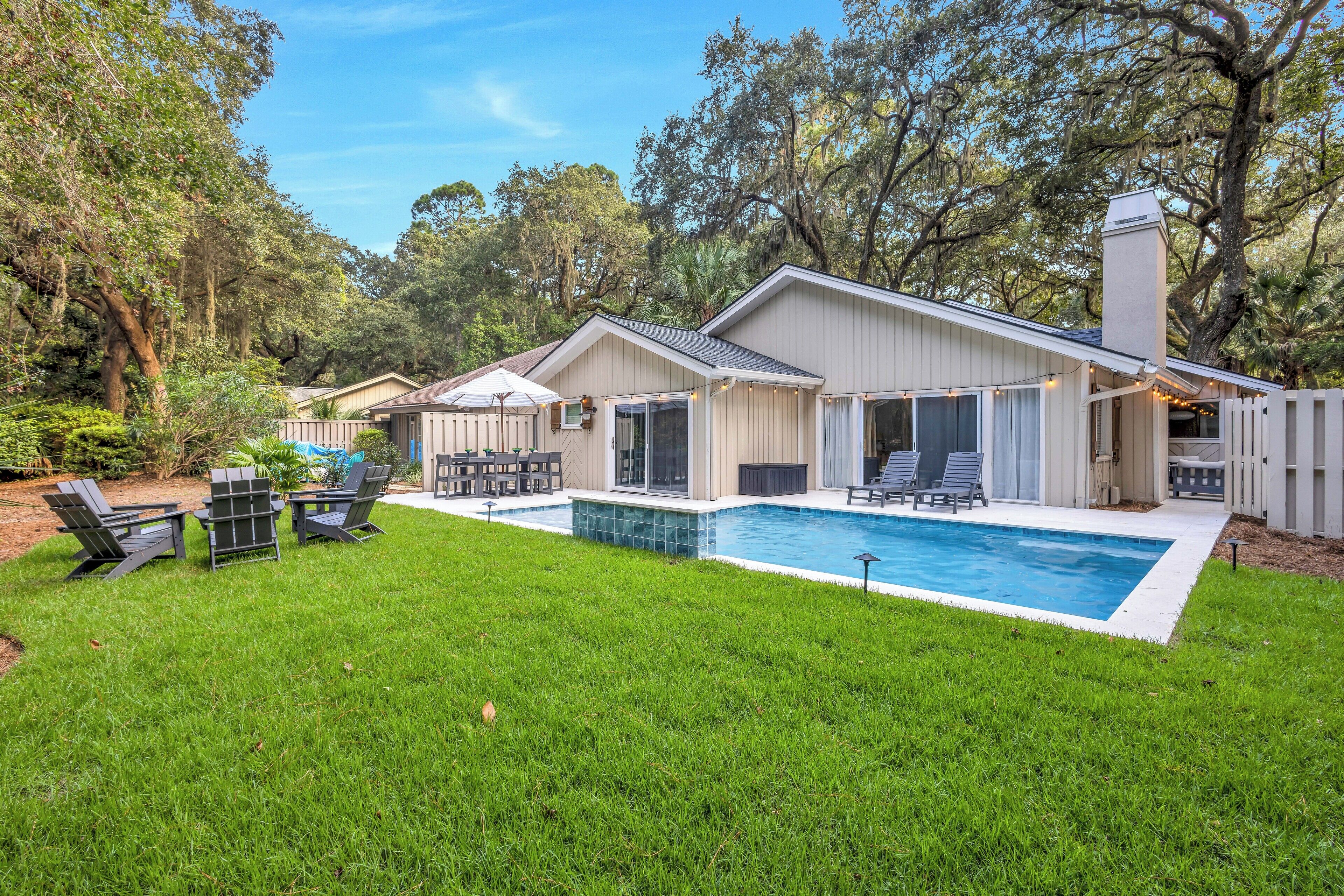 A house with a swimming pool, outdoor furniture, and a covered patio area.