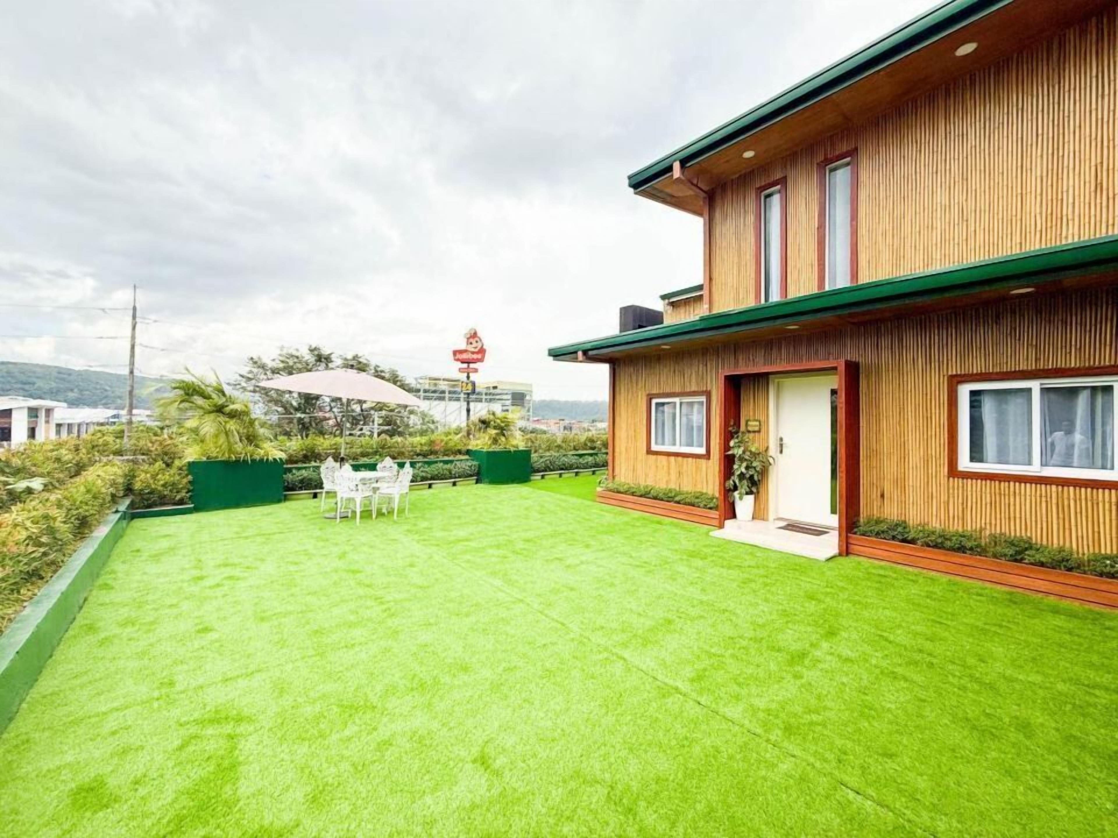 A modern house with a well-maintained lawn and a dining area with outdoor furniture.