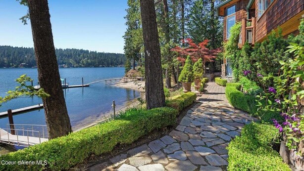 A lakeside property with a stone pathway leading to a dock, surrounded by lush greenery and a wooden cabin. - Chateau Lac Hayden-Lake Front Luxury w/ Boats & Polaris rentals, lots of toys (Hayden)