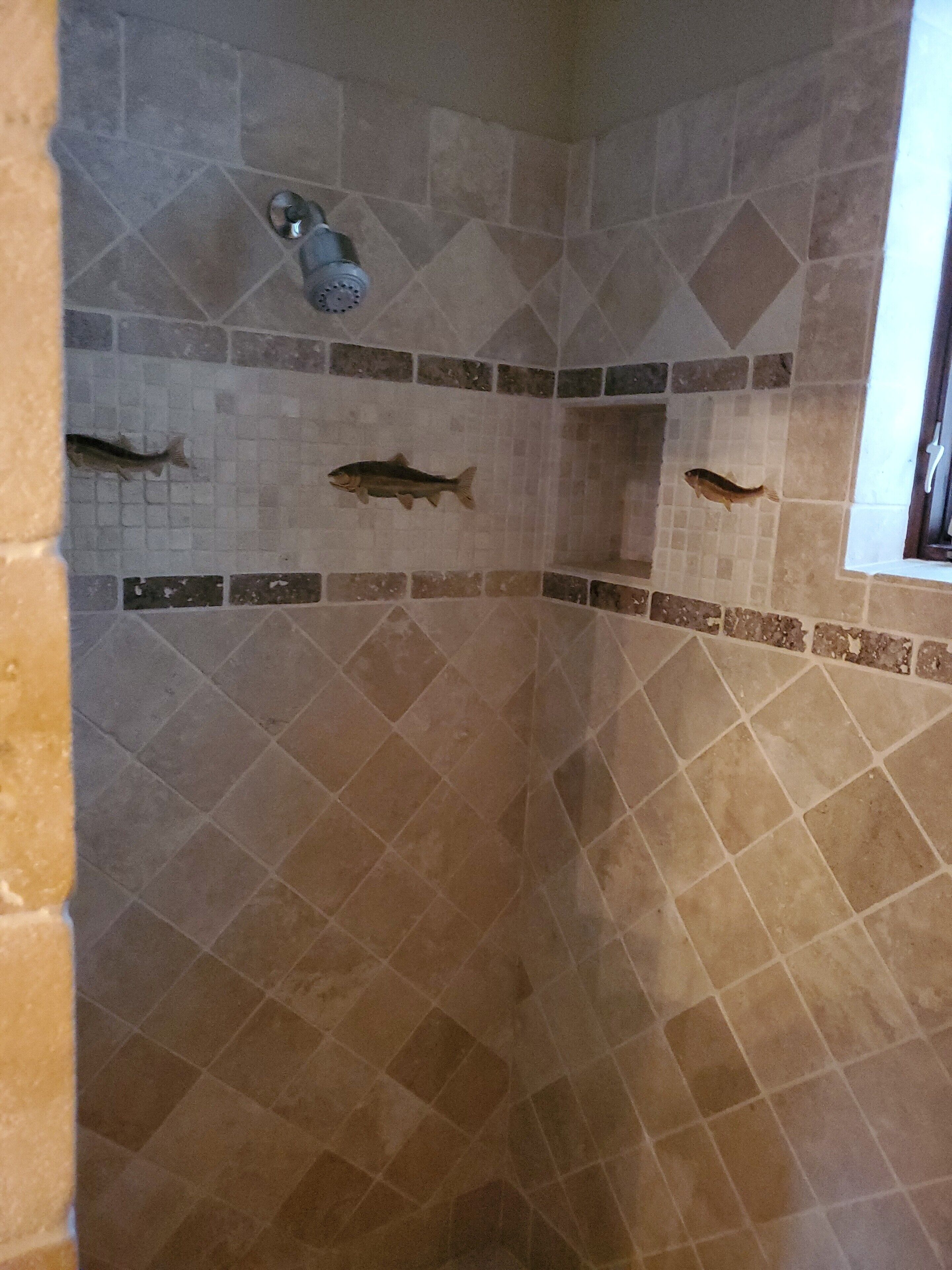 A shower with mosaic tiles and three fish decorations.
