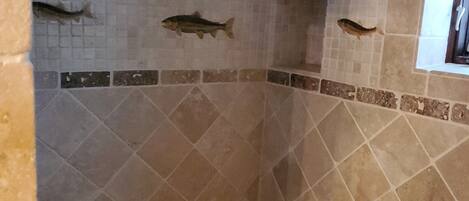 A shower with mosaic tiles and three fish decorations.