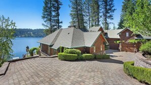 A house with a paved driveway, a wooden deck, and a view of a lake. - Chateau Lac Hayden-Lake Front Luxury w/ Boats & Polaris rentals, lots of toys (Hayden)