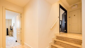 Ein Korridor mit Holzboden, einer weißen Tür und einer Treppe, die zu einem anderen Raum führt.
