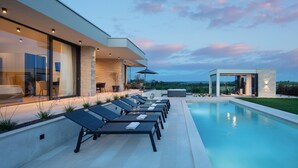 A modern poolside area with lounge chairs, a pool, and a view of the landscape. - Lovely home in Brtonigla with sauna (Brtonigla)
