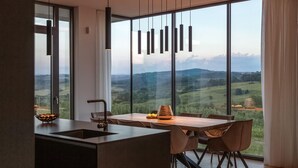 A modern kitchen with a large island, a dining area with a view of rolling hills, and pendant lighting. - Lovely home in Brtonigla with sauna (Brtonigla)