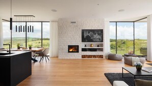 A modern living room with a fireplace, a dining area, and large windows offering a scenic view. - Lovely home in Brtonigla with sauna (Brtonigla)