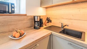 Una cucina moderna con un piano di lavoro in legno, una macchina da caffè, un lavandino e un forno a microonde.