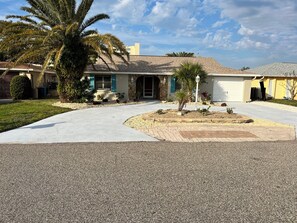 Una casa residencial amb una entrada, un jardí davant ben cuidat i una palmera.